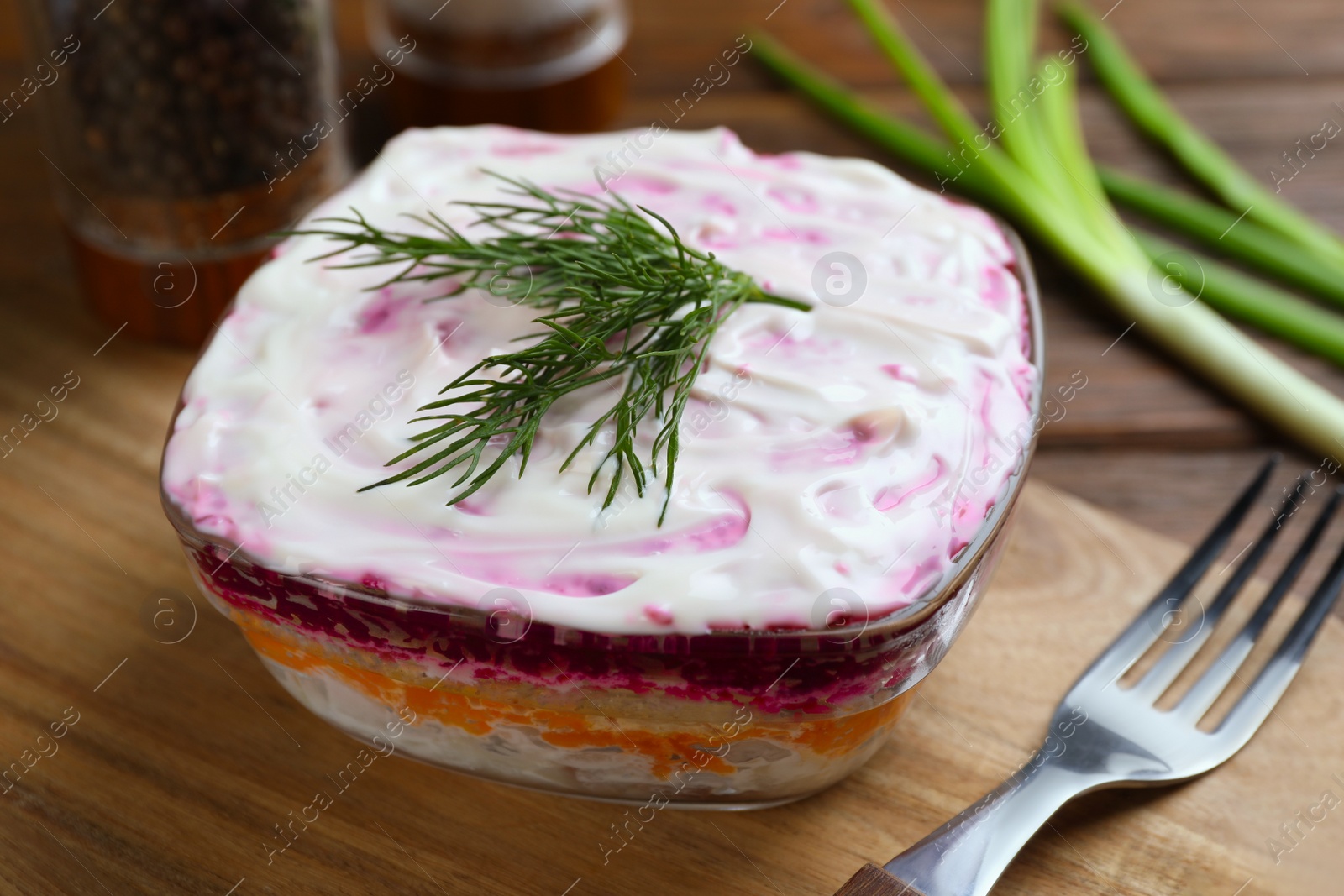 Photo of Herring under fur coat on wooden table. Traditional Russian salad