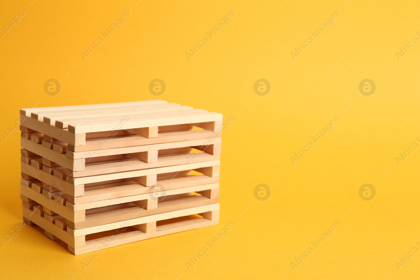 Photo of Stack of wooden pallets on orange background, space for text