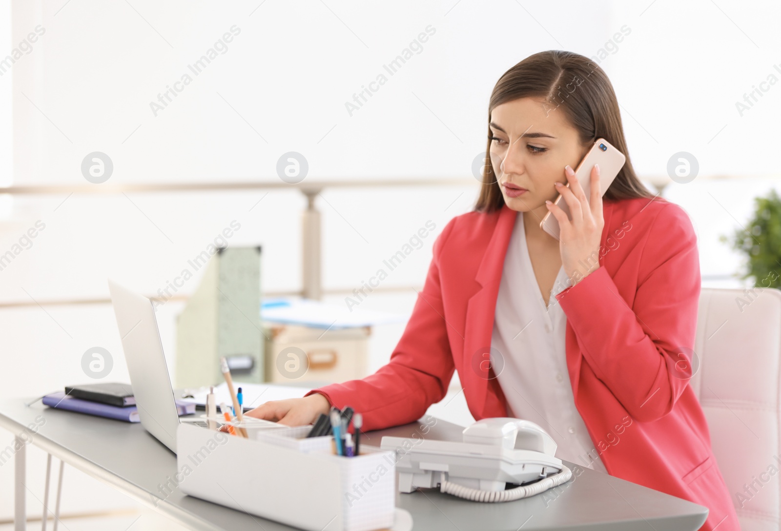 Photo of Young woman talking on phone at workplace