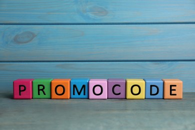 Photo of Colorful cubes with words Promo Code on grey table, space for text