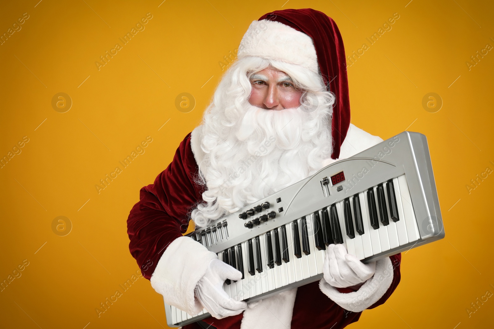 Photo of Santa Claus with synthesizer on yellow background. Christmas music