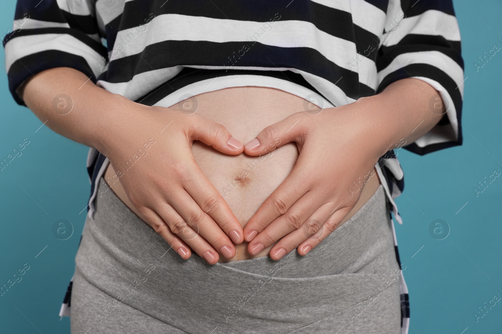 Photo of Pregnant woman on light blue background, closeup