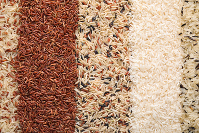 Photo of Different types of rice as background, top view