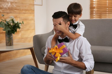 Man receiving gift for Father's Day from his son at home
