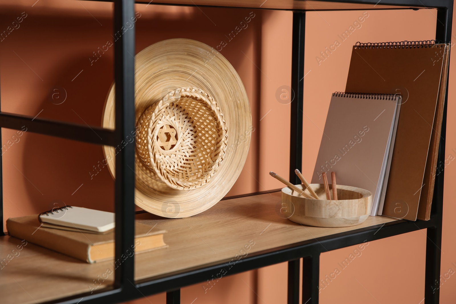 Photo of Stylish shelving unit with decorative elements near color wall. Interior design