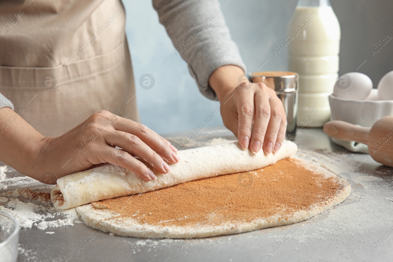 Photo of Woman making cinnamon rolls at table, closeup