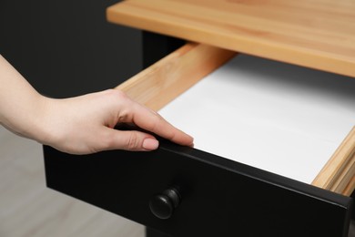 Photo of Woman opening empty desk drawer indoors, closeup view