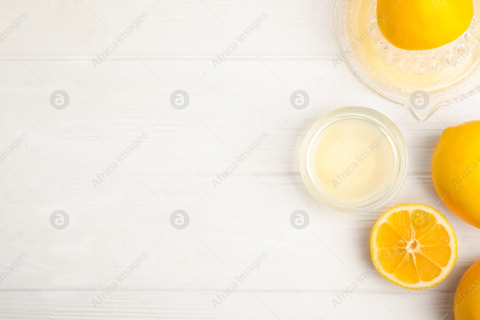 Photo of Freshly squeezed lemon juice on white wooden table, flat lay. Space for text