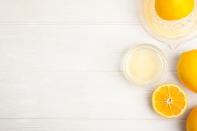 Freshly squeezed lemon juice on white wooden table, flat lay. Space for text