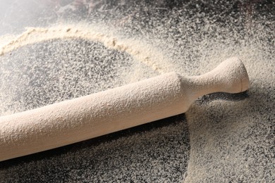 Photo of Scattered flour and rolling pin on table, closeup