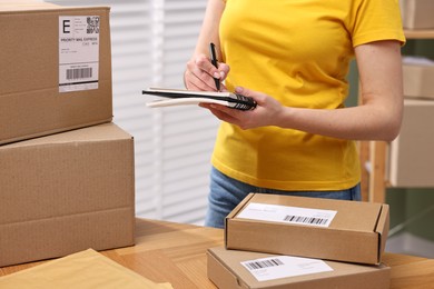 Photo of Parcel packing. Post office worker writing notes indoors, closeup