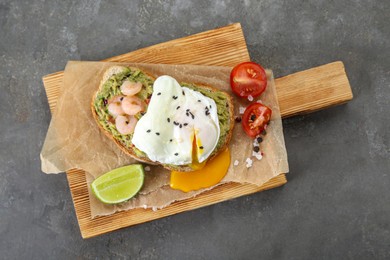 Photo of Delicious sandwich with guacamole, shrimps and fried egg on grey table, top view