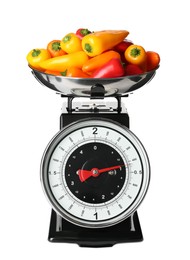 Photo of Heap of ripe bell peppers on mechanical kitchen scales against white background