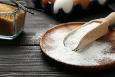 Photo of Pate and scoop with baking powder on black wooden table, closeup