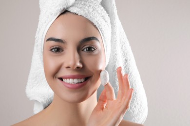 Photo of Woman using silkworm cocoon in skin care routine on light grey background. Space for text