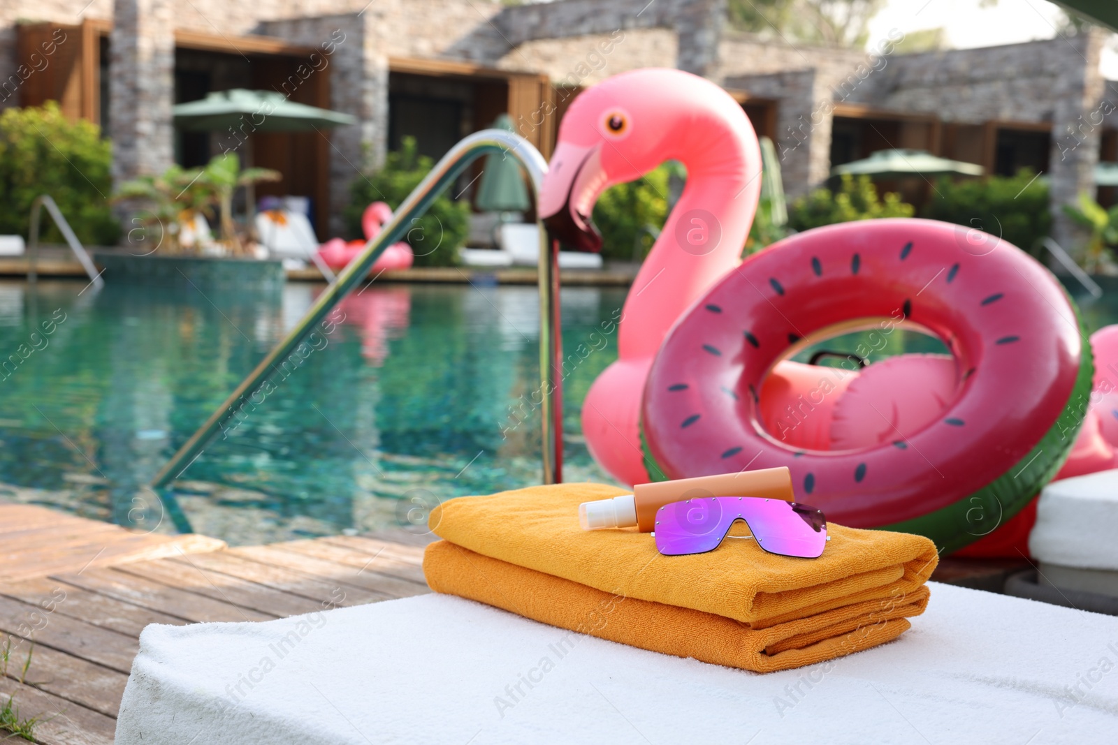 Photo of Beach accessories on sun lounger, inflatable ring and float near outdoor swimming pool at luxury resort