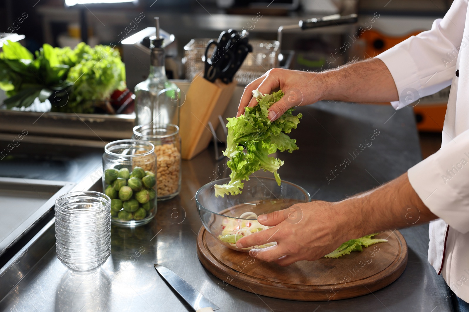 Photo of Professional chef making salad in restaurant kitchen, closeup