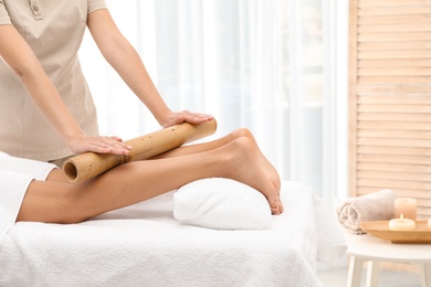 Woman having massage with bamboo stick in wellness center