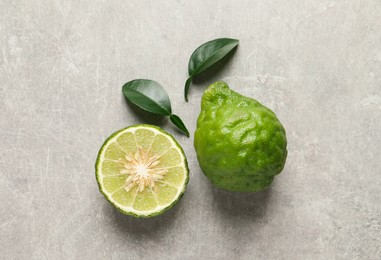 Photo of Fresh ripe bergamot fruits with green leaves on light grey table, flat lay
