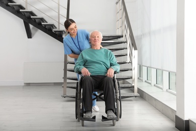 Nurse assisting senior man in wheelchair at hospital