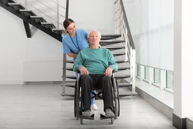 Photo of Nurse assisting senior man in wheelchair at hospital