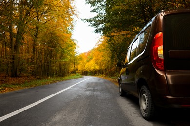 Photo of Modern car on asphalt road near autumn forest