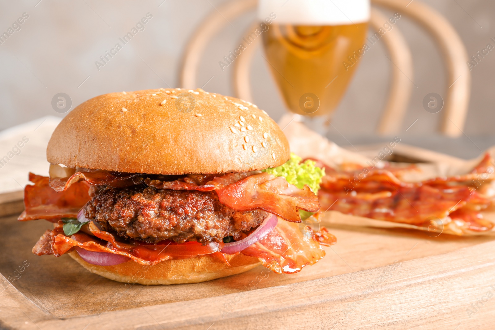 Photo of Tasty burger with bacon on wooden board