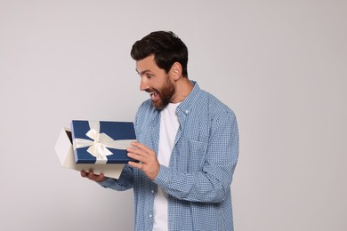 Photo of Emotional man opening gift box on light grey background