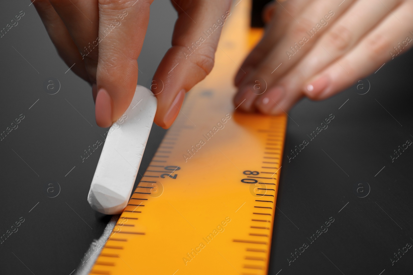 Photo of Woman drawing with chalk and ruler on blackboard, closeup