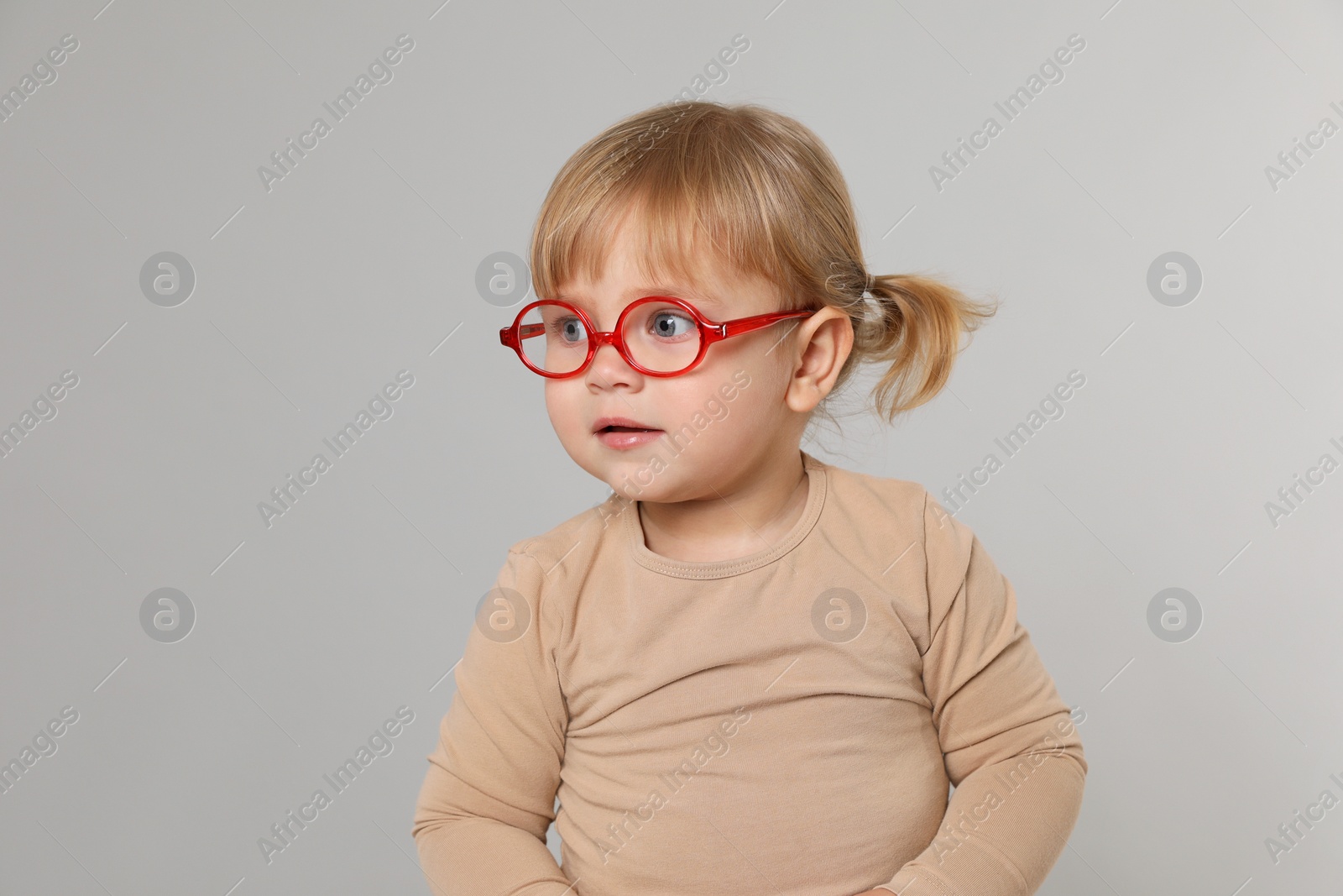 Photo of Cute little girl in glasses on light grey background. Space for text