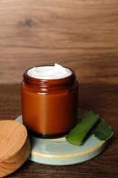 Photo of Jar of face cream and aloe vera leaves on wooden table