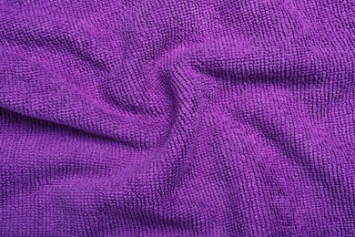 Photo of Crumpled purple microfiber cloth as background, closeup