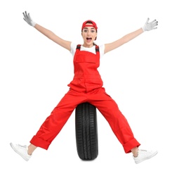 Female mechanic in uniform with car tire on white background