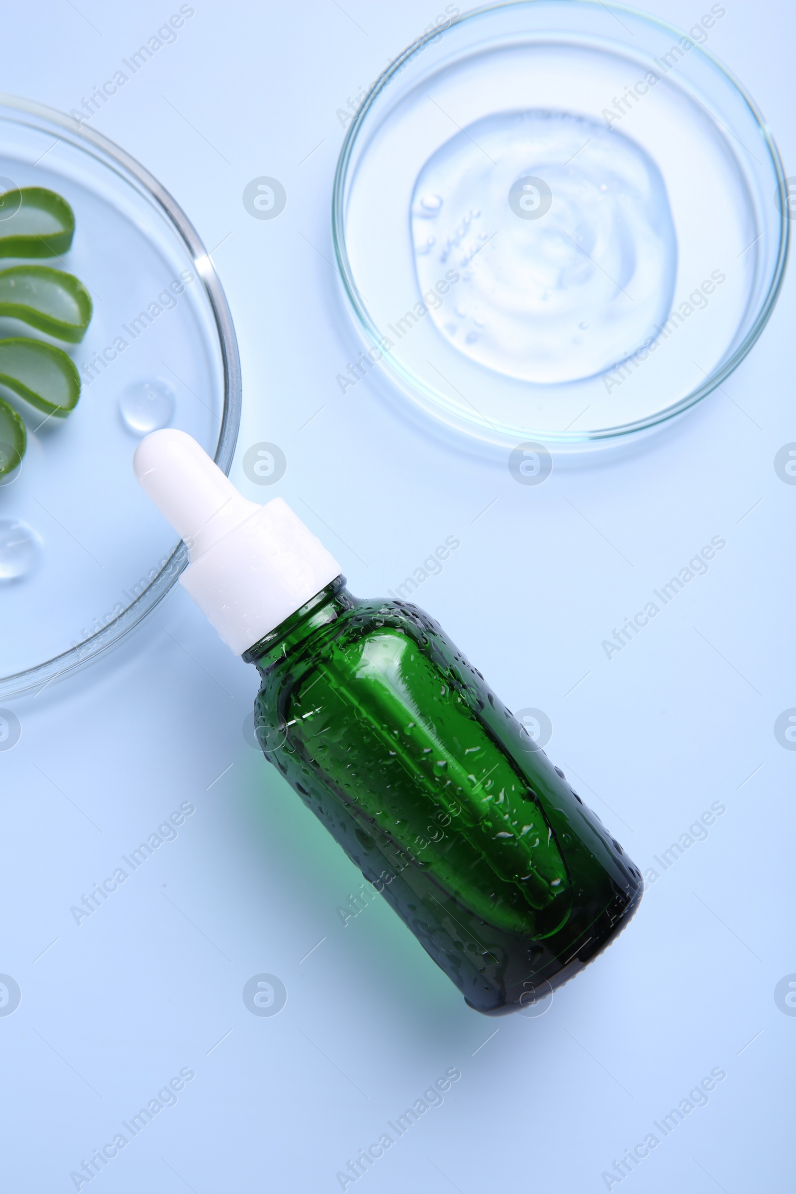 Photo of Cut aloe vera, bottle and cosmetic gel on light blue background, flat lay