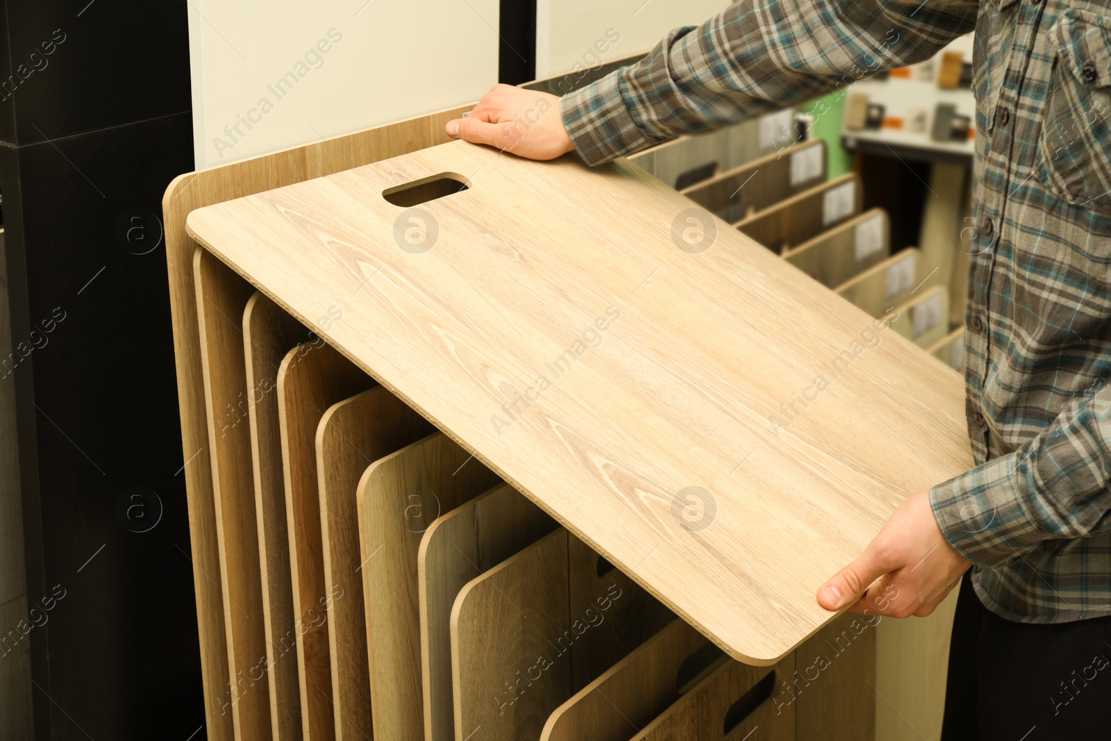 Photo of Man with sample of wooden flooring in shop, closeup