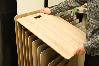 Man with sample of wooden flooring in shop, closeup