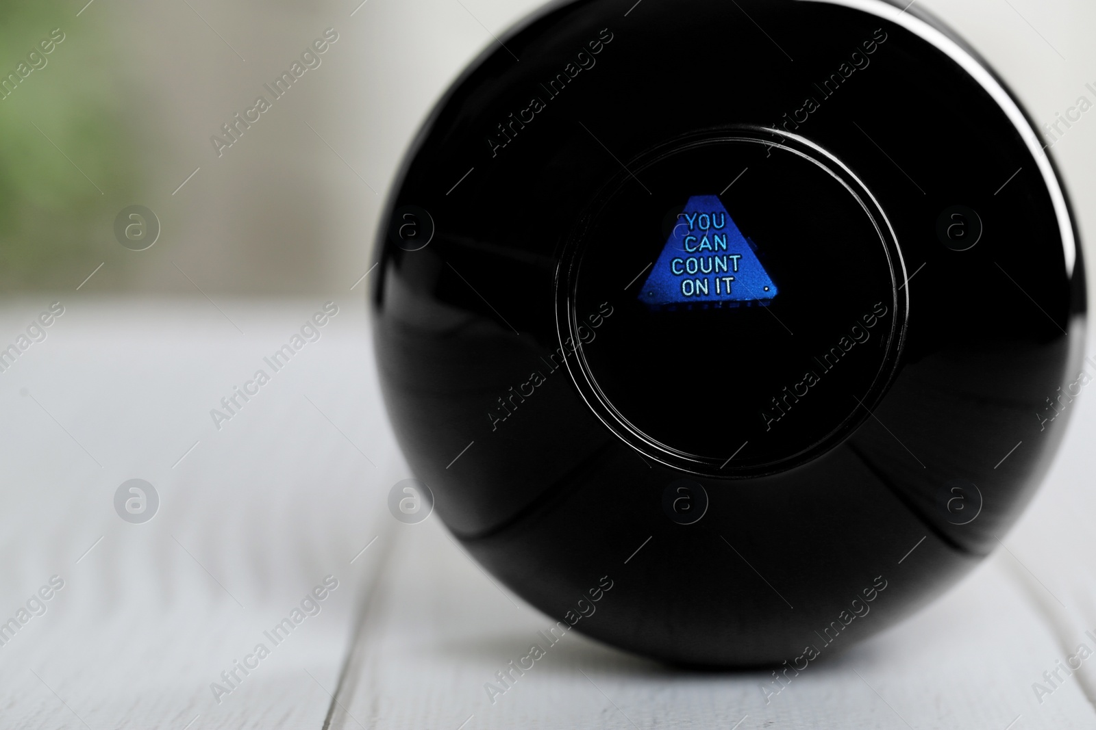 Photo of Magic eight ball with prediction You Can Count On It on light table, closeup. Space for text