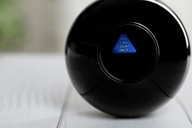 Magic eight ball with prediction You Can Count On It on light table, closeup. Space for text