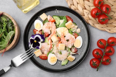 Delicious Caesar salad with shrimps served on grey table, flat lay