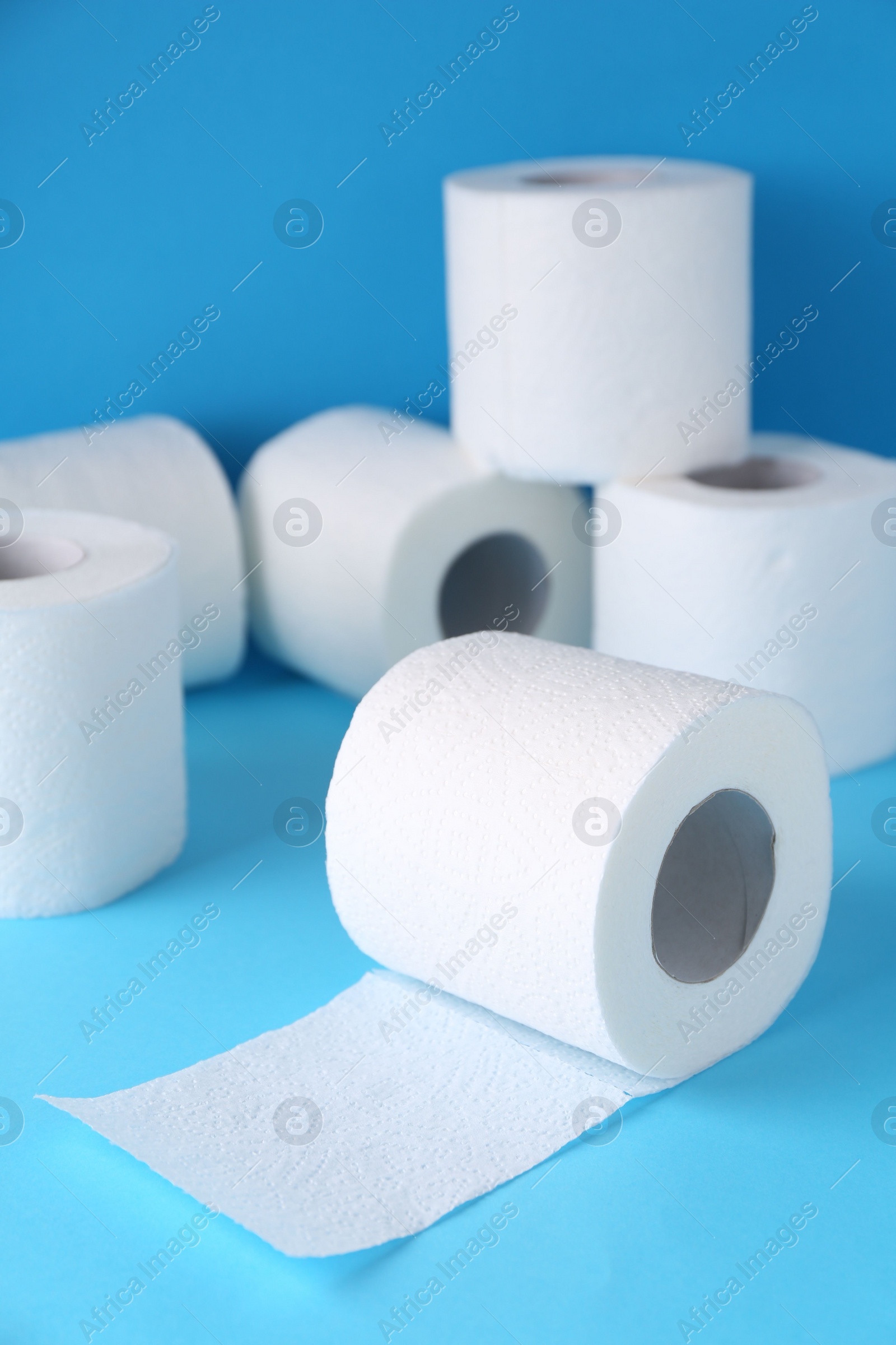 Photo of Soft toilet paper rolls on light blue background, closeup