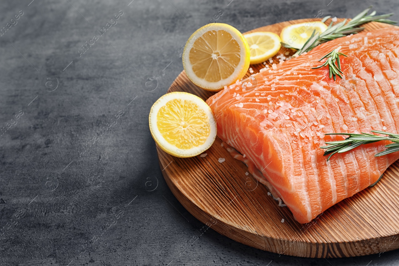 Photo of Wooden board with raw salmon and ingredients for marinade on grey background