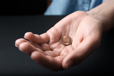 Photo of Young woman holding coins on black background, closeup view