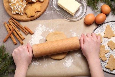 Photo of Making Christmas cookies. Woman rolling raw dough at grey table, top view