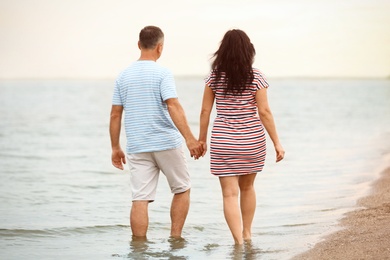 Happy mature couple walking together on sea beach