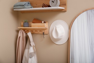 Photo of Hallway interior with stylish accessories and wooden hanger for keys on beige wall