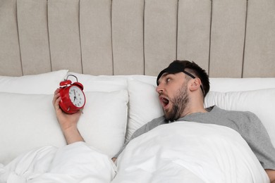Photo of Emotional overslept man with alarm clock in bed, above view. Being late concept