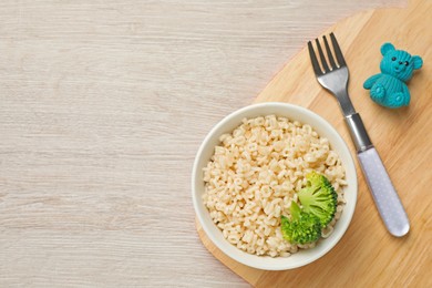 Photo of Bowl with tasty pasta and broccoli on white wooden table, top view. Space for text