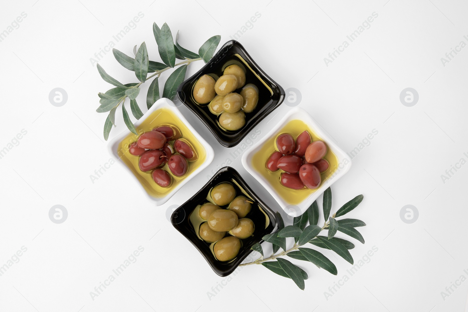 Photo of Bowls with different ripe olives and leaves on white background, flat lay