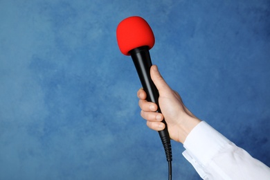 Woman holding microphone on color background, space for text