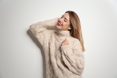 Beautiful young woman in warm sweater on white background